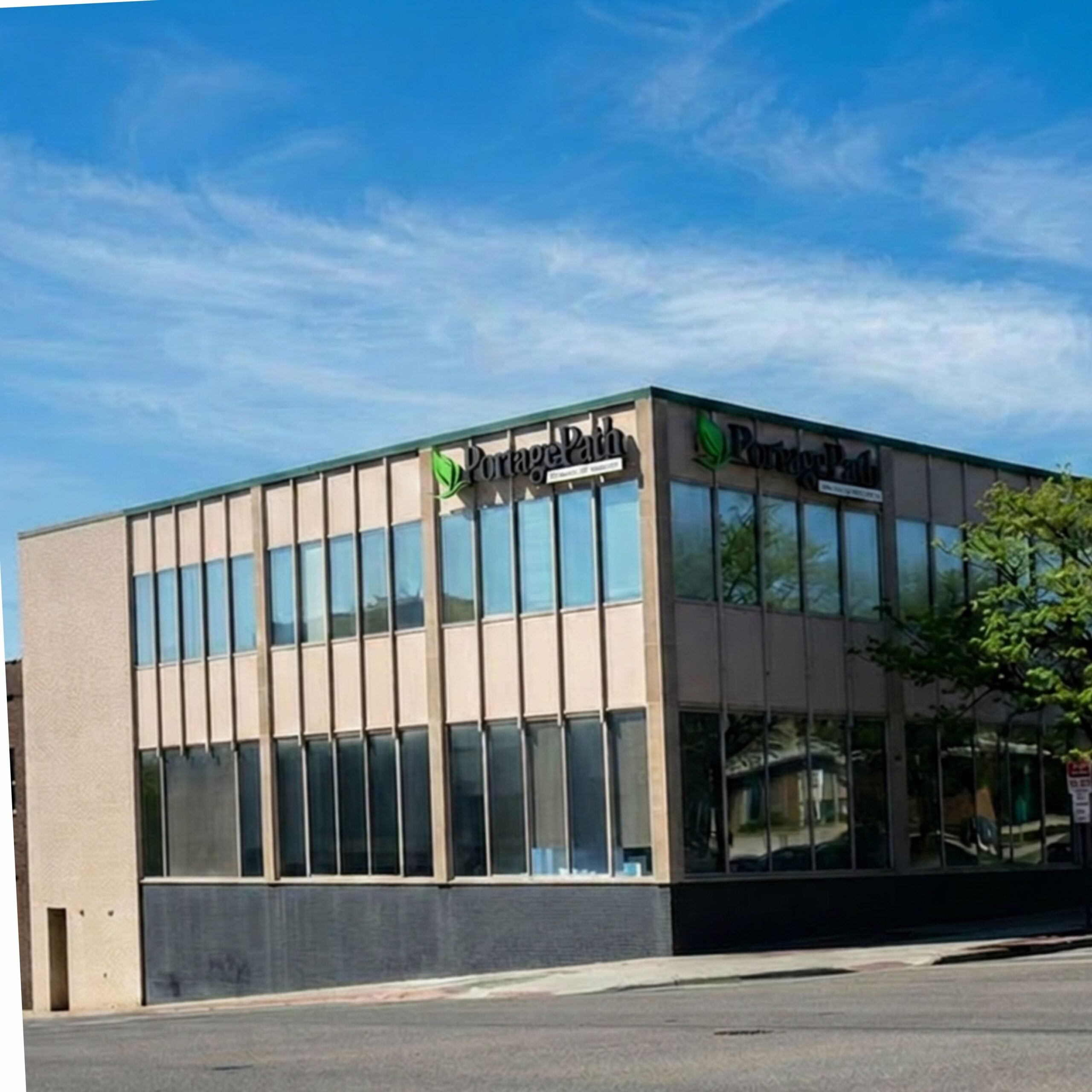 Akron Outpatient Exterior | Portage Path Behavioral Health Modern office building with tall glass windows and a portage path sign featuring a green leaf logo on the facade.