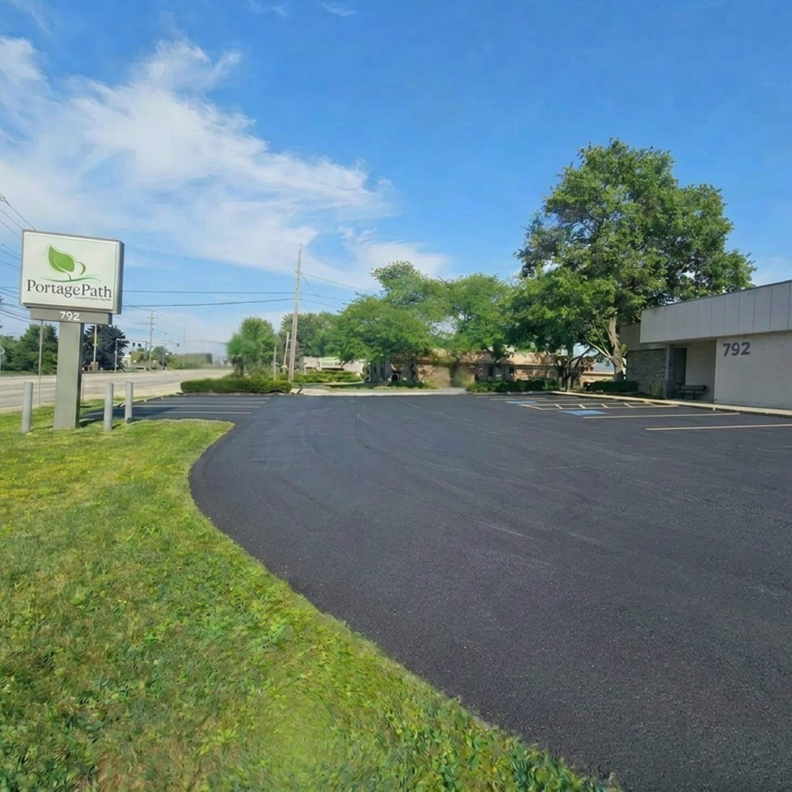 North Summit Parking Lot Photo | Portage Path Behavioral Health Portagepath sign beside an empty parking lot with green hedges and a blue sky.