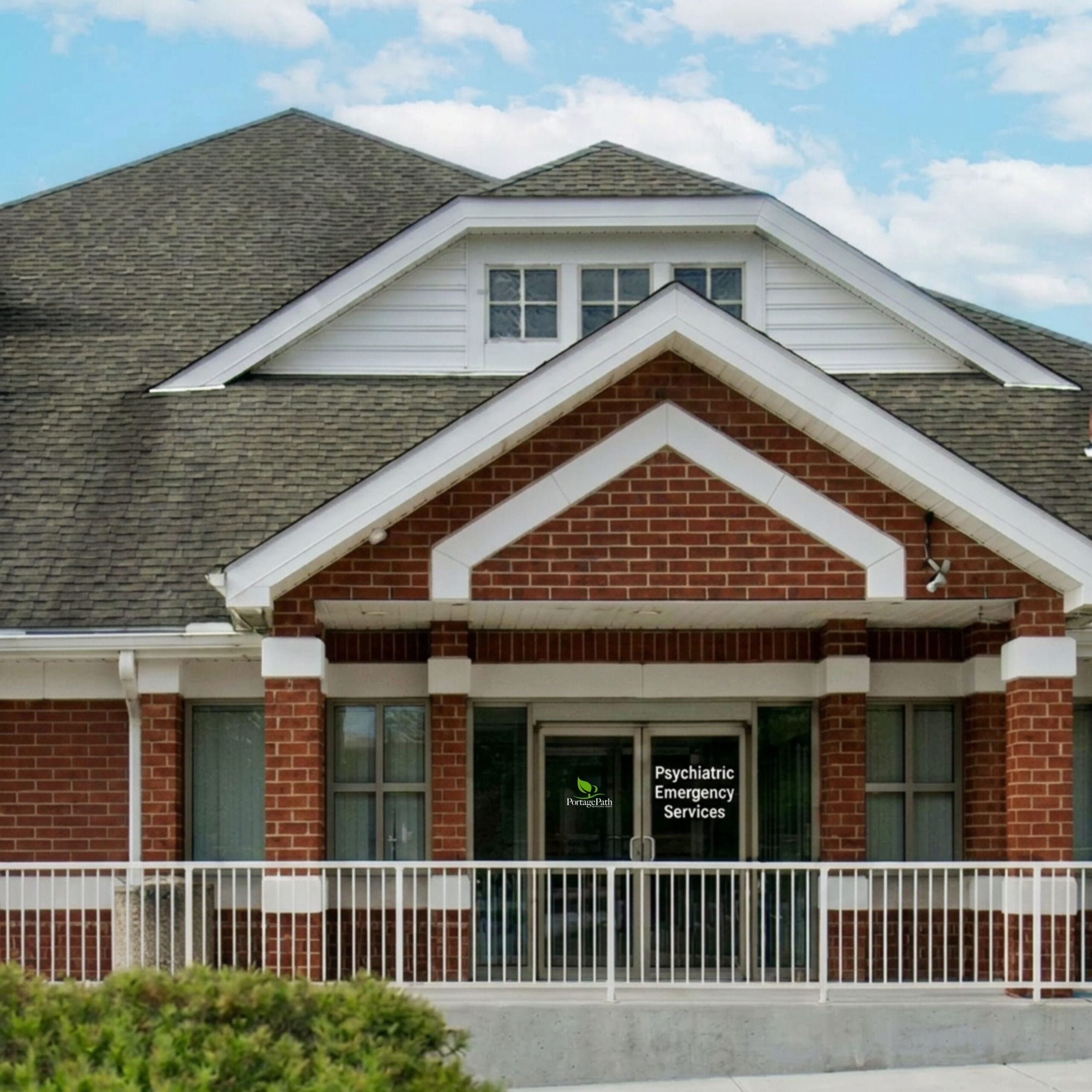 Pes Exterior | Portage Path Behavioral Health Front of a brick building with white trim and glass doors; sign reads psychiatric emergency services near the entrance.